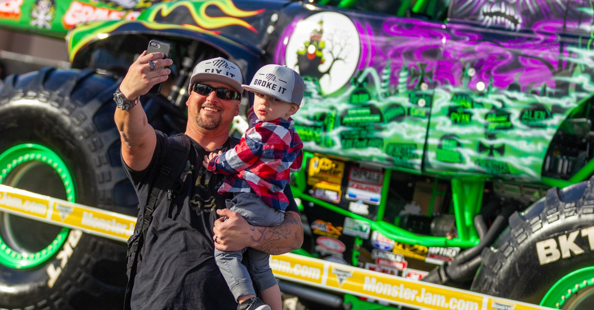 Monster Jam fan with child taking a photo in front of Grave Digger