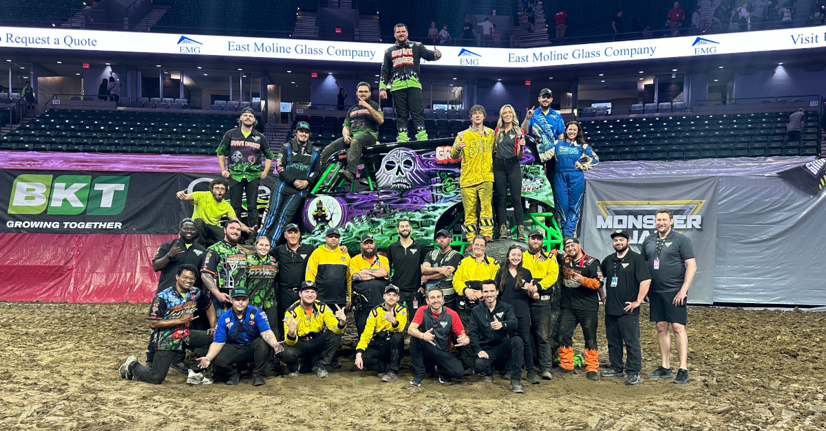 The drivers and crew of Arena Championship Series West pose for a photo in front of Grave Digger.