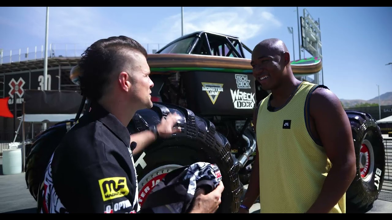 Video screengrab of two men talking while standing in front of a Monster Jam truck