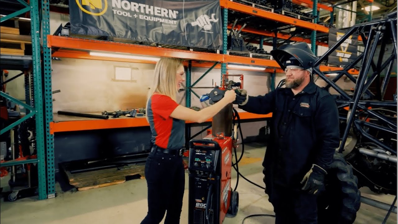Monster Jam host Casey Gagliardi and a mechanic in the Monster Jam workshop give each other a fist bump